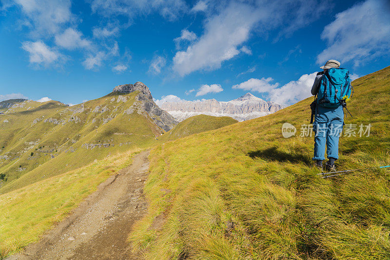 在意大利北部Dolomites的Viel dal Pan小径上休息时，老妇人享受萨斯·德·卡佩罗峰的美丽景色。